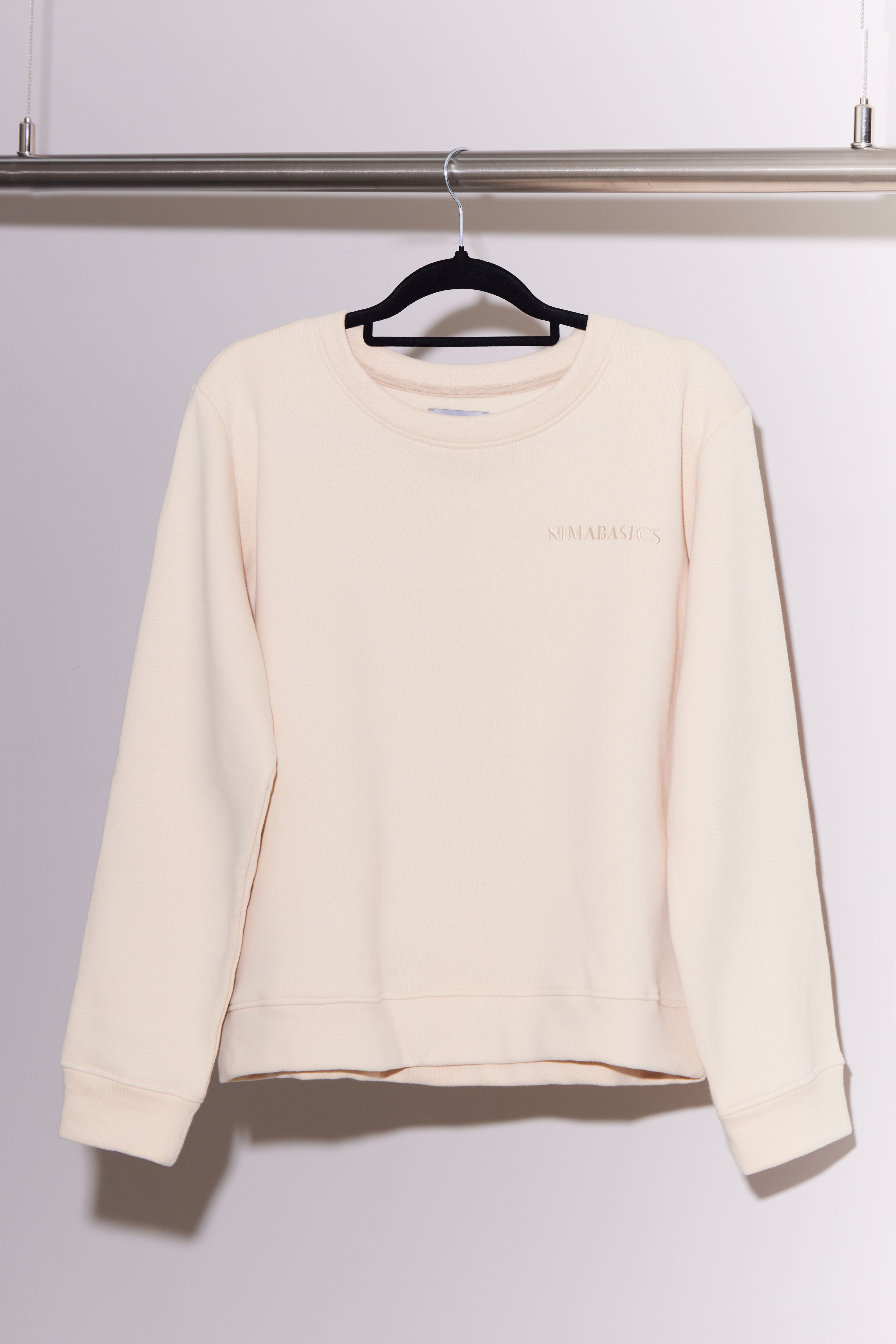 Beiger Sweater hängt an Kleiderstange