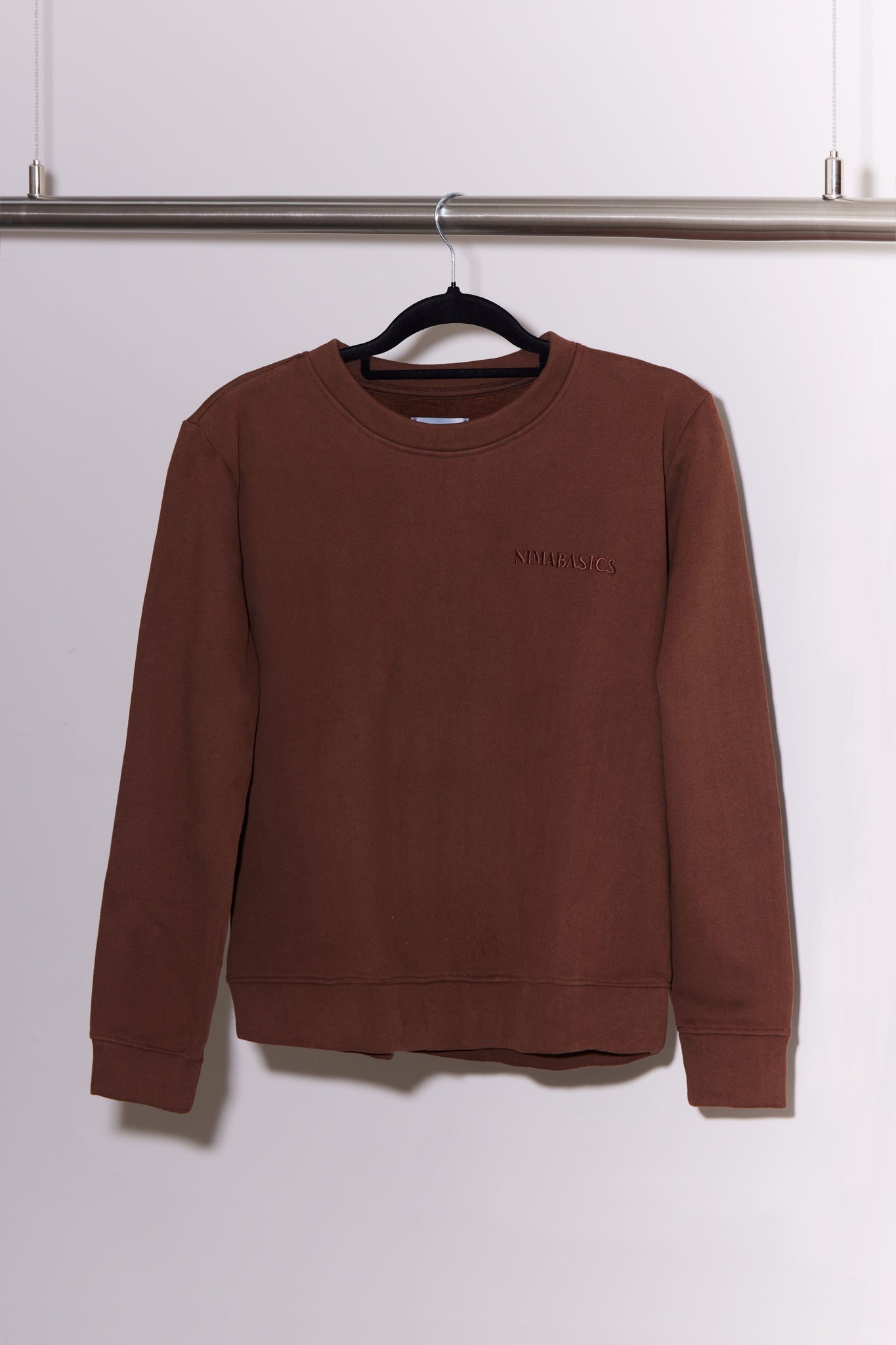 Brauner Sweater hängt an Kleiderstange