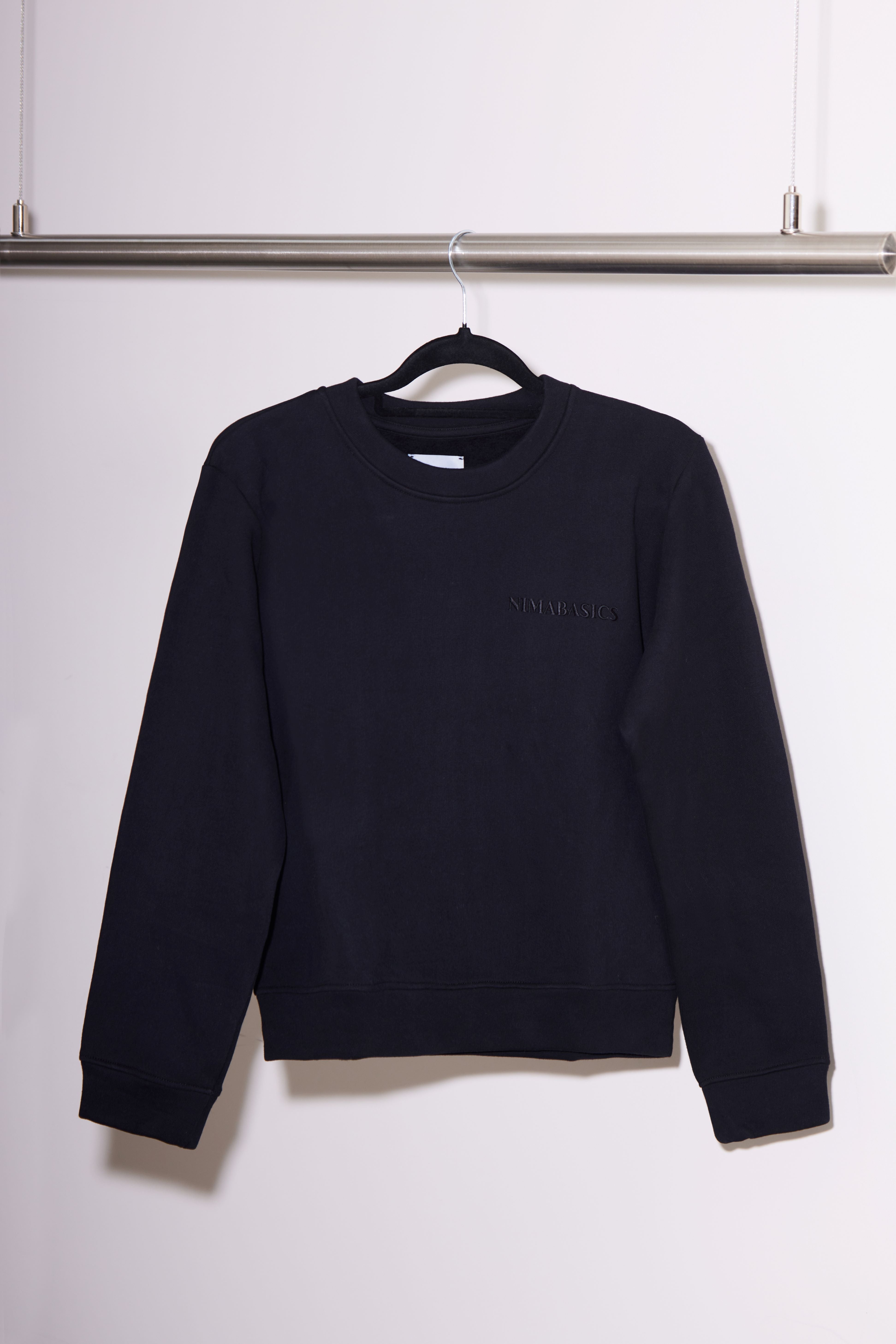 Sweater schwarz hängt an Kleiderstange